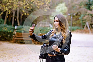 Charming young female in trendy outfit smiling and taking selfie