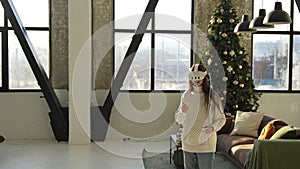 A charming young girl donning a virtual reality visor with a Christmas tree in the background.