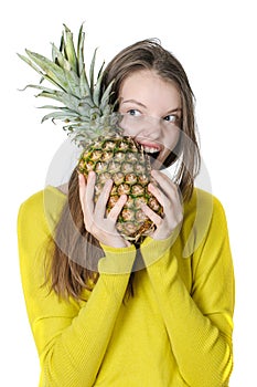 Charming young girl gnaws a large pineapple. photo