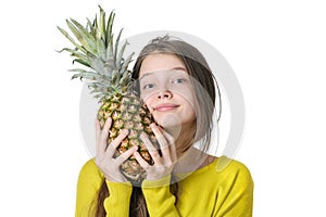 Charming young girl presses to face large ripe pineapple.