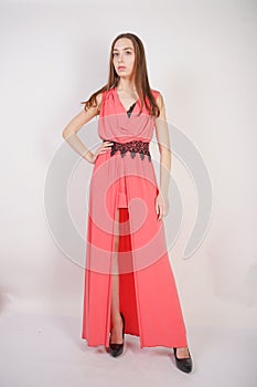 Charming young girl in red evening long dress with black lace stands on a white background in the Studio