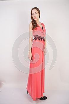 Charming young girl in red evening long dress with black lace stands on a white background in the Studio