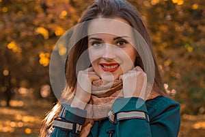 Charming young girl with red lipstick on lips holding hands and smiling scarf