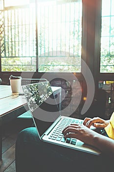 charming young hipster girl hands working on her laptop sitting at wooden table in a coffee shop.