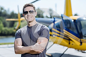 Charming young pilot posing at a helipad