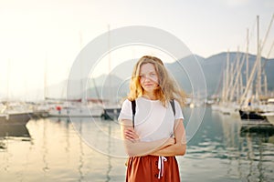 Charming young tourist woman travel by Mediterranean coast. Attractive red-haired girl on the background of sea and yachts. Yacht