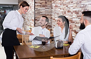 Charming young waiter receiving order from guests
