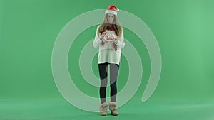 Charming young woman in Christmas hat tries to realise what lies in her Xmas present, chroma key on background