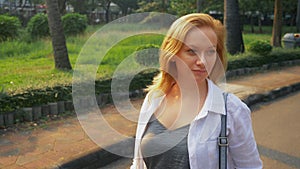 Charming young woman with golden hair rushing in the city center.