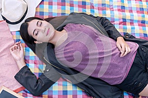 Charming young woman with hat sleeping on mat picnic felling relaxation. Teenager girl lying on the cloth picnic happiness while