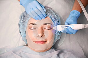 Charming young woman having skincare procedure in beauty salon.