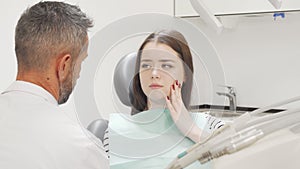 Charming young woman having toothache visiting her dentist