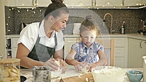 Charming young woman and her 5-6 year old daughter cook a dough together. Pleasant and rewarding pastime.