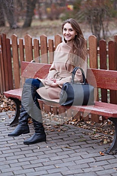 Charming young woman with long brown hair in a beige coat