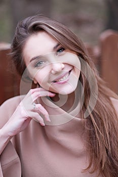 Charming young woman with long brown hair in a beige coat