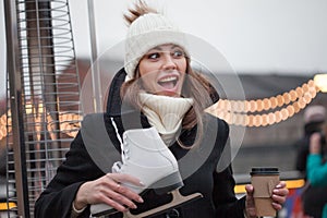 Charming young woman in the Park near the ice rink. Smiling brunette with skates