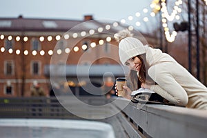 Charming young woman in the Park near the ice rink. Smiling brunette with skates