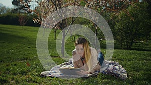 Charming young woman reading a book in spring park