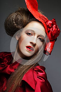 Charming young woman in a red carnival costume and hat. Fashionable woman ready for a party