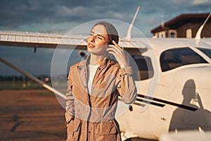 Charming young woman standing near plane at airdrome