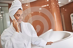 Charming young woman talking on cellphone after taking bath