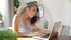 Charming young woman typing on laptop computer at home.