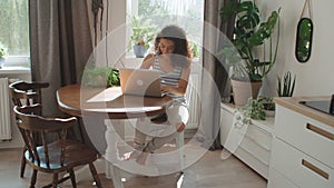 Charming young woman typing on laptop computer at home.