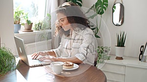 Charming young woman typing on laptop computer at home.