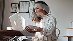 Charming young woman typing on laptop computer at home.