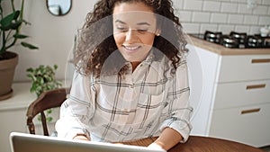 Charming young woman typing on laptop computer at home.