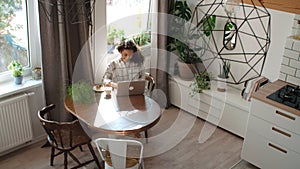 Charming young woman typing on laptop computer at home.