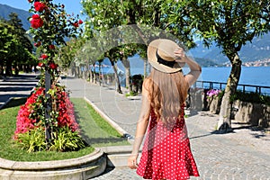 Charming young woman walking along Bellagio flowered promenade on Lake Como, Italy