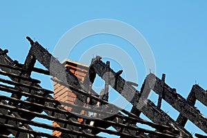 Charred burnt black wooden roof structure after house fire