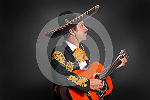 Charro Mariachi playing guitar on black photo