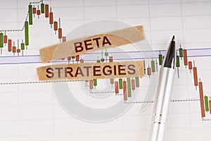 On the chart of business quotes lies a pen and torn paper with the inscription - Beta Strategies