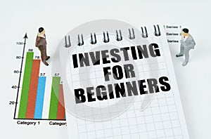 On the chart there are miniature figures of businessmen and a notepad with the inscription - INVESTING FOR BEGINNERS