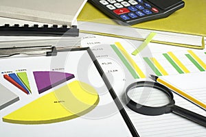 Charts, accounting books, calculator and magnifying glass on wooden office table. Financial and budget concept.