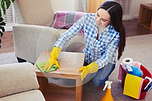 Charwoman carefully cleaning with mop small coffee table