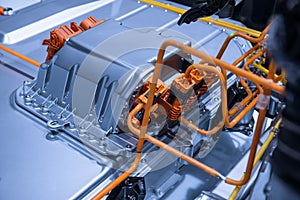 Chassis of the electric car with powertrain and power connections closeup. Blue toned. EV car drivetrain at maintenance.