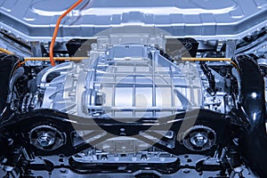 Chassis of the electric car with powertrain and power connections closeup. Blue toned. EV car drivetrain at maintenance.