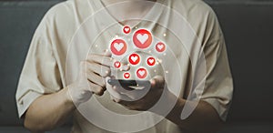 Chat and notification on smartphone with virtual red heart emoji social media icon. Man using smartphone on vacation with hologram