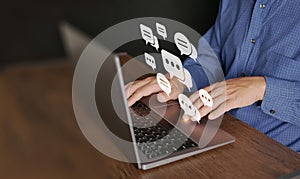 Chat and stay connected via internet. A man uses computer laptop for online communication. Virtual speech bubbles or balloon icons