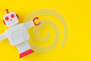 Chatbot or AI Artificial Intelligence or robotic concept, cute vintage look plastic robot on vivid yellow background