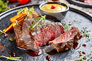 Chateaubriand beef tenderloin steak on a dark plate. cooked to medium rare perfection and is glistening with juices. grilled
