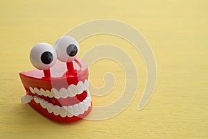 Chattering teeth toy wind up moving on yellow background. Funny, comedy, relax time