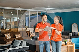 chatting couple in red using a tablet standing in furniture store department