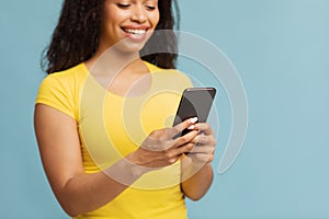 Chatting with friends. Happy black woman using smartphone texting sms message over blue background, selective focus