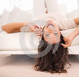 Chatting with the person she loves most. A woman lying upside down on a sofa while chatting on the phone.