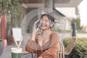 A chatty Asian woman is on the phone with her friends laughing about a funny joke