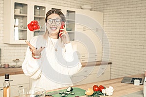 Chatty lady playing with vegetables while talking on mobile phone